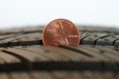 A penny sitting in the groove of a tire