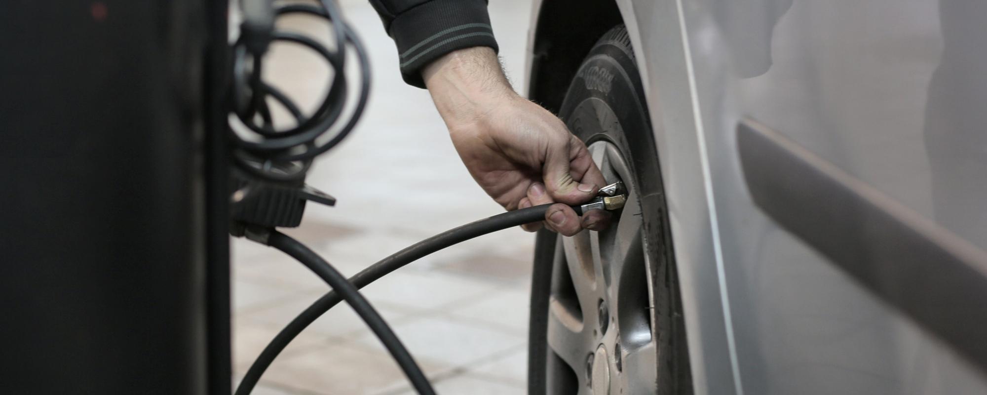 Car technician filling a tire with air